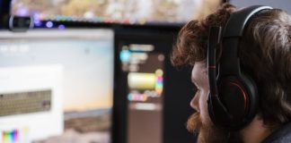 Beyond Pixels: Unraveling the Intricate Tapestry of Modern Game Design Free Man with headset concentrating on work at dual monitors in a home office setting. Stock Photo