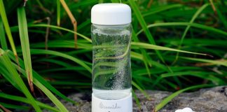 a glass bottle with water inside sitting on a rock