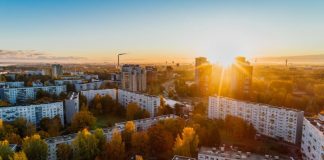 Aerial view of a cityscape at sunrise with autumn foliage and modern buildings.
