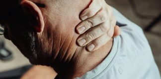 Man with neck pain holding his neck in discomfort, conveying tension or stress.