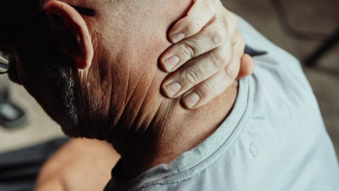 Photo by Kindel Media Man with neck pain holding his neck in discomfort, conveying tension or stress.