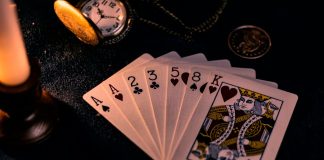A dimly lit close-up of playing cards with a pocket watch, showcasing a nostalgic casino vibe.