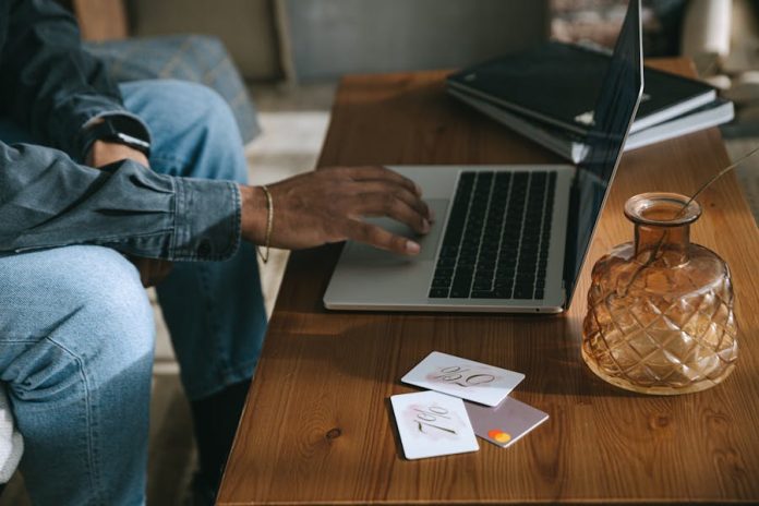 Photo by Ivan Samkov Person shopping online using a laptop with discount cards placed on a wooden table.