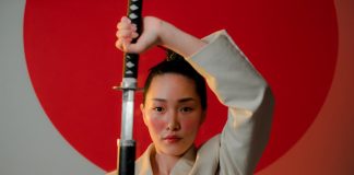 A striking portrait of a resilient woman in a blazer holding a katana, emphasizing strength and elegance.