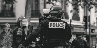 grayscale photo of Police standing and leaning on wall
