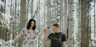 man holding hands with woman near trees