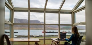person in blue jacket sitting on brown wooden chair near brown wooden table during daytime