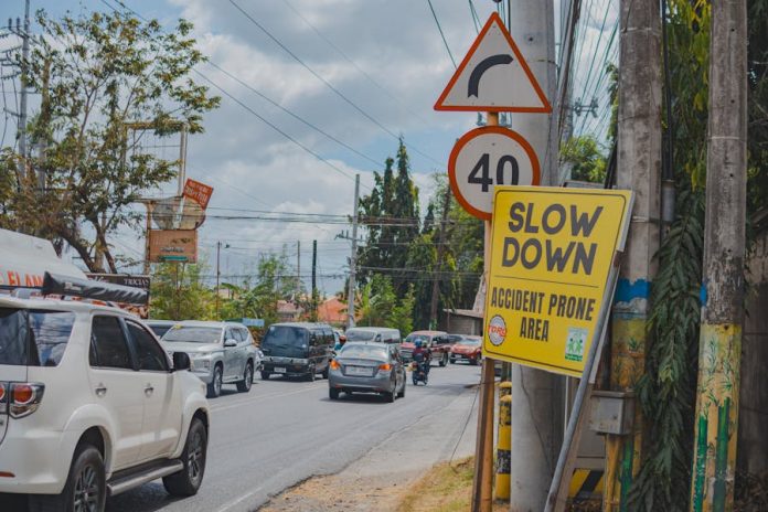 Heavy urban traffic on a city street with visible road signs. Vehicles and road safety signs dominate the scene.
