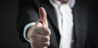 A close-up of a man's thumbs up gesture, symbolizing success and agreement.