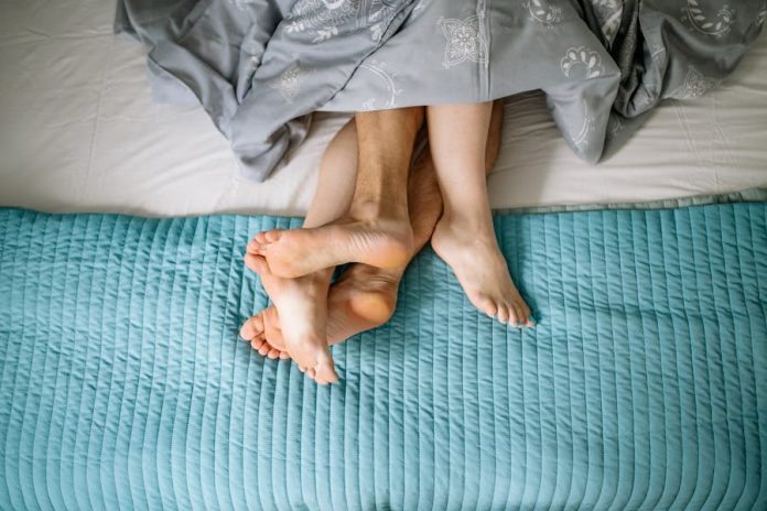 Photo by Yan Krukau A cozy, intimate moment with a couple's feet intertwined on a bed, showcasing love and relaxation.