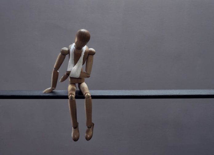 Photo by Marco Bianchetti A wooden mannequin sits sadly with a bandage.