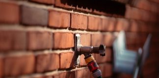 A faucet and garden hose attached to brick wall.