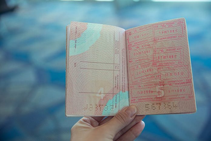 Photo by Ekaterina Belinskaya Close-up view of an open passport displaying various travel stamps in an airport setting.