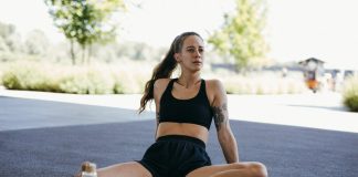 Explore The Top Benefits Of Using A Copper Bottle In Everyday Life Athletic woman in black sports attire resting outdoors, capturing a moment of relaxation and fitness.