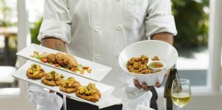 person in white dress shirt holding white ceramic bowl with food