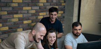 A group of people sitting around a laptop computer