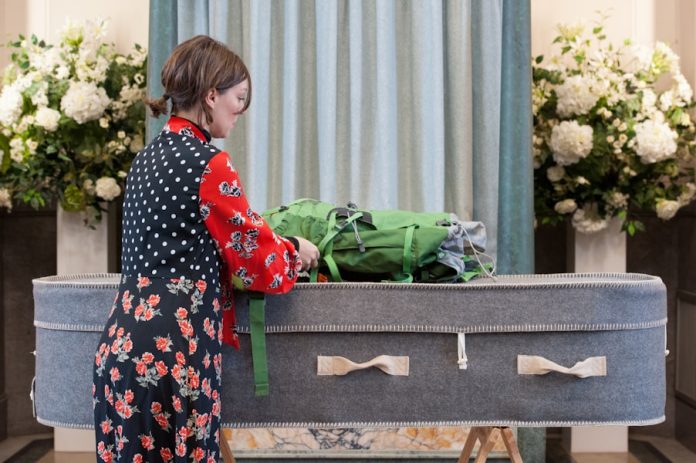 Photo by The Good Funeral Guide a woman standing in front of a suitcase