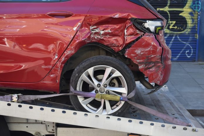 Photo by Usman Malik a red car is on a flatbed tow truck