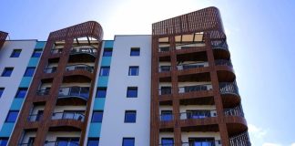 Explore the contemporary design and architecture of urban apartments with wooden accents and blue sky backdrop.