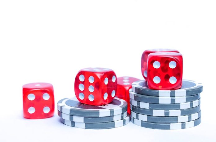 Photo by Sascha Düser Vibrant red dice stacked with poker chips, ideal for gambling themes.