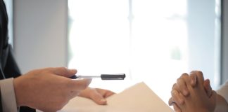Close-up of a contract signing with hands over documents. Professional business interaction.