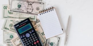 Flat lay of US dollar bills with calculator and notebook for budgeting.