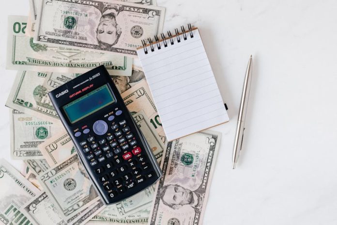 Photo by Photo By: Kaboompics.com Flat lay of US dollar bills with calculator and notebook for budgeting.