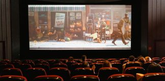 A cozy indoor movie theater showing an animated film to a small audience.