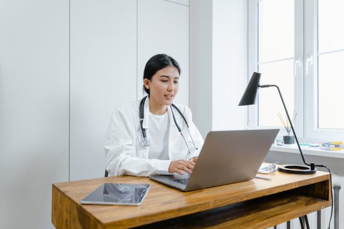 Photo by Tima Miroshnichenko A female doctor in a white coat uses a laptop for an online consultation from her office.