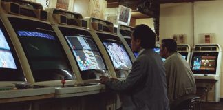 a man playing a video game in front of a row of slot machines