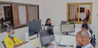 A group of people sitting around a table with laptops