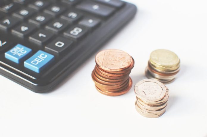 Photo by Breakingpic Close-up of stacked coins and a calculator symbolizing financial strategy and budgeting.