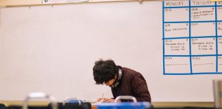 A high school student studying and solving problems in a classroom setting.