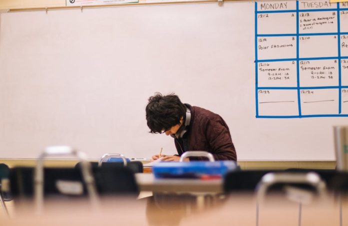 Photo by Jeswin Thomas A high school student studying and solving problems in a classroom setting.