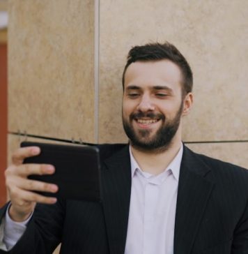 Step-by-Step Guide to Register for the Tiranga Colour Prediction Game Man in suit smiling while looking at tablet