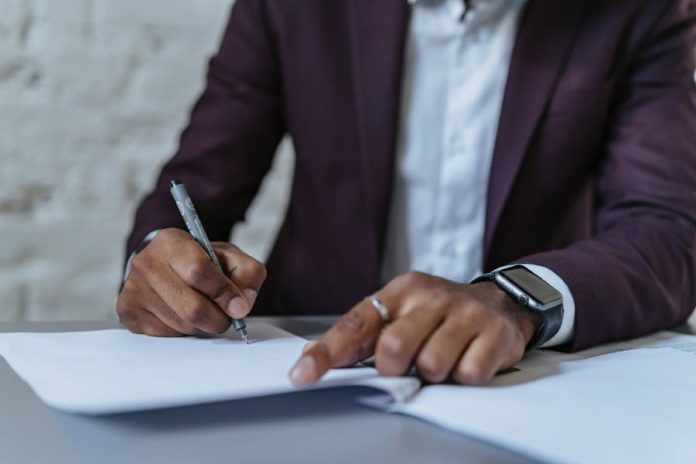 Photo by olia danilevich Close-up of a man signing documents in an office. Business-focused and professional environment.