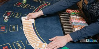 5 Casino Games to Try When Visiting an Online Casino A casino dealer skillfully spreads playing cards on a gaming table, surrounded by colorful poker chips.