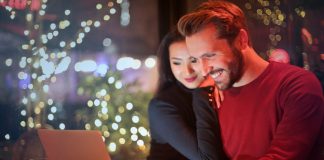 First look at the Ozwin Casino gaming platform for Australian players A couple using a laptop at a cozy restaurant with festive bokeh lights, enjoying online shopping together.