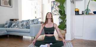 a woman sitting on a yoga mat in a living room