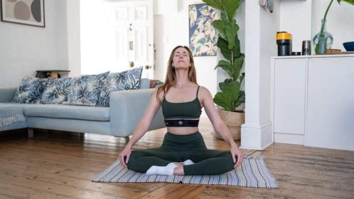 a woman sitting on a yoga mat in a living room