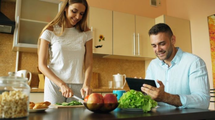 Photo by Vitaly Gariev Couple preparing food and using tablet in kitchen.