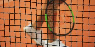 How to Choose the Right Tennis Racket for Your Skill Level from Best Tennis Shop in Dubai person wearing pair of white low-top sneakers while holding Wilson tennis racket