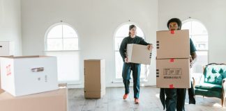 Moving Services Guide For Smoother Shifts And Stress-Free Packing Two movers carrying boxes in a sunlit room, ready to assist with relocation.