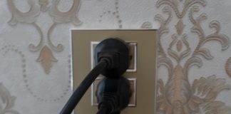 Two black plugs inserted into a gold electrical outlet.
