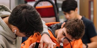 boy in orange shirt holding red and black backpack