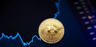 Golden bitcoin coin on background of chart showing indicators of changes in cryptocurrency rates