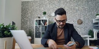 a man sitting at a table in front of a laptop