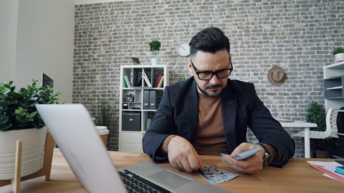 Photo by Vitaly Gariev a man sitting at a table in front of a laptop