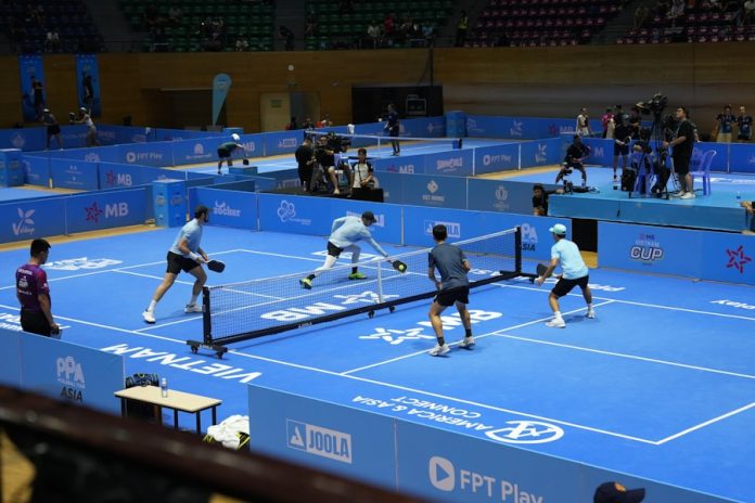 Players compete in a pickleball match on a blue court.