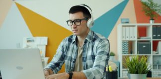 Man wearing headphones works on a laptop.